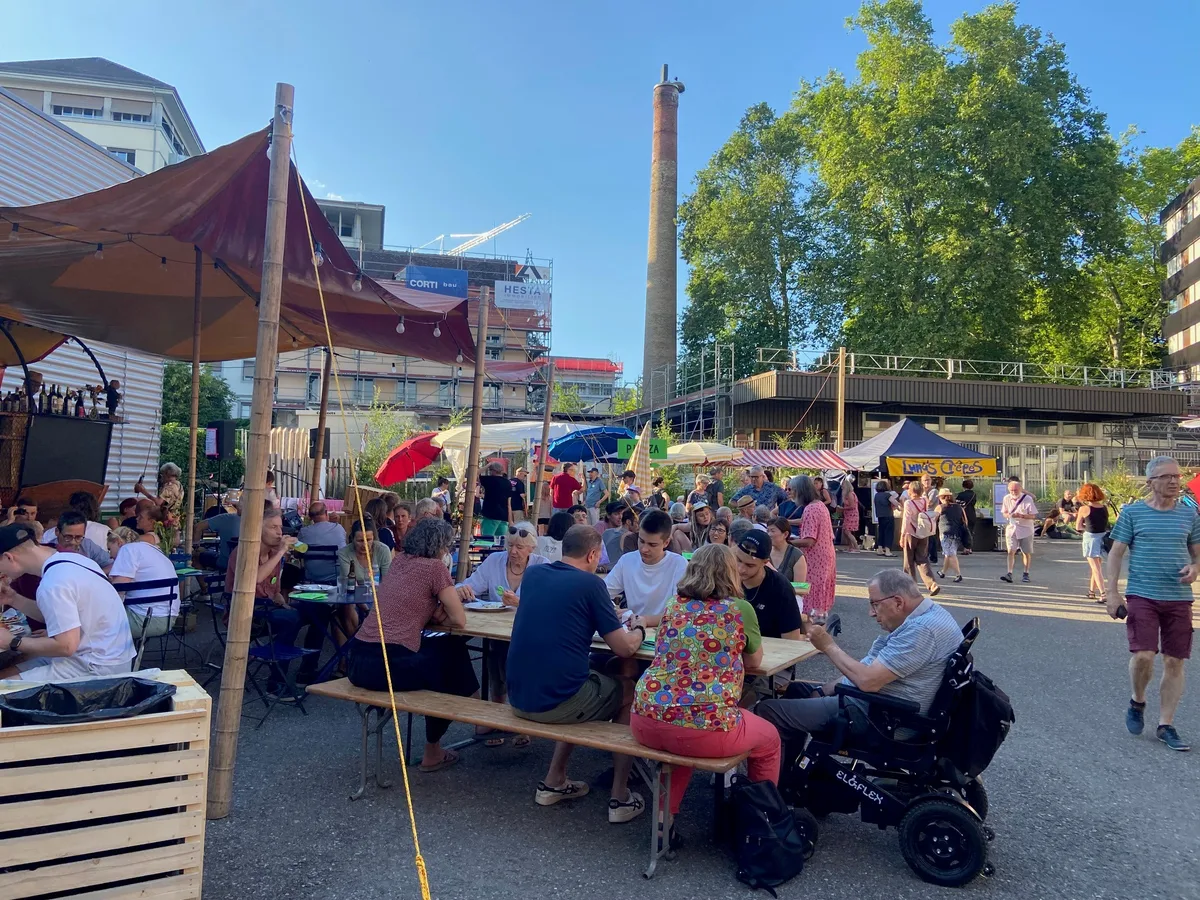 Menschen, die an Festbänken sitzen und zu Abend essen.